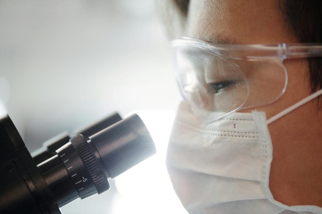 Close-up of a scientist wearing protective gear examining samples in a laboratory setting.